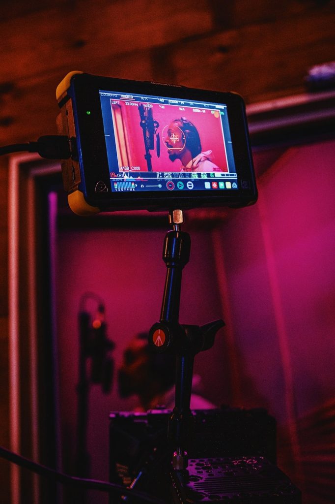 Camera monitor showing an artist being filmed under pink light