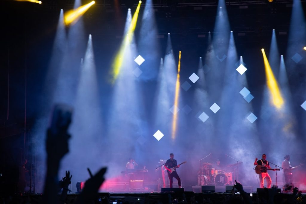 Band performing on a stage lit with blue and pink lights
