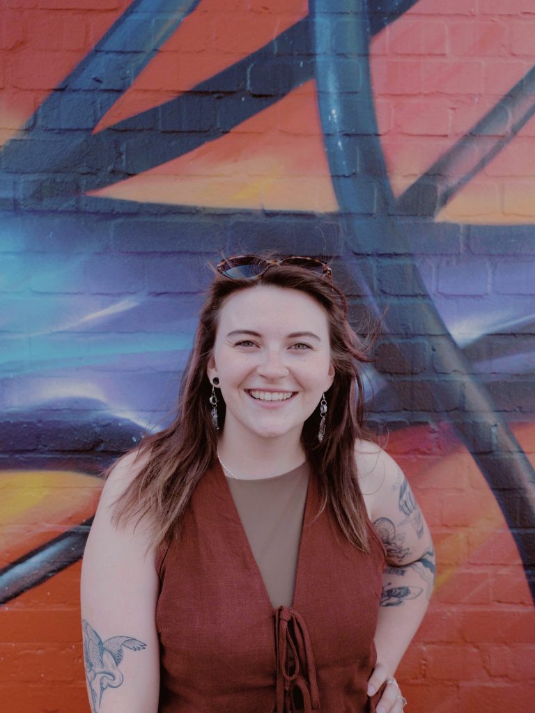 Miri, artist development mentor and music producer in Bristol, smiling in front of a graffiti wall